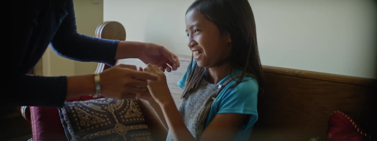 Mother tickles her daughter on a couch in the living room