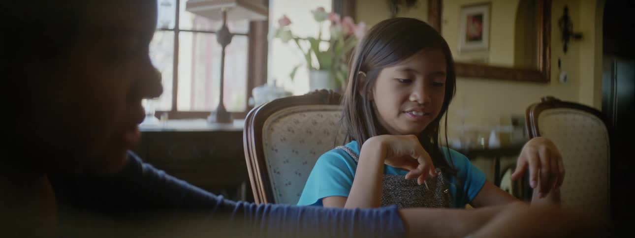 Woman with blue shirt and girl with light blue t shirt play marshmallow game at table