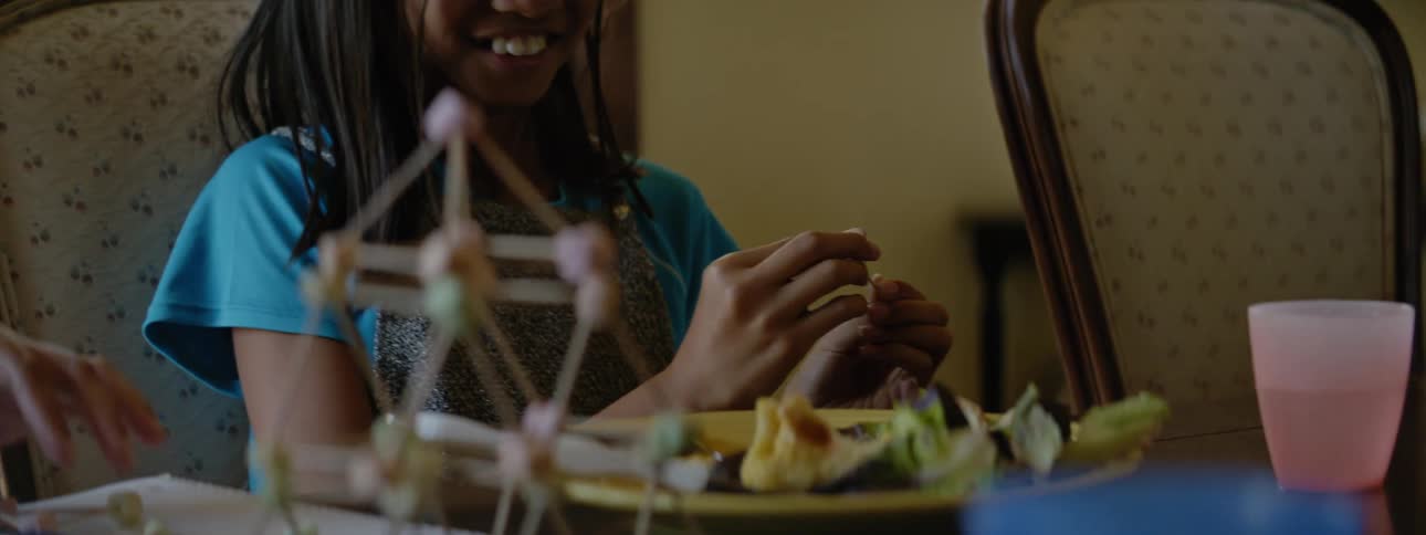 Mother and daughter have fun assembling a model while eating lunch at home