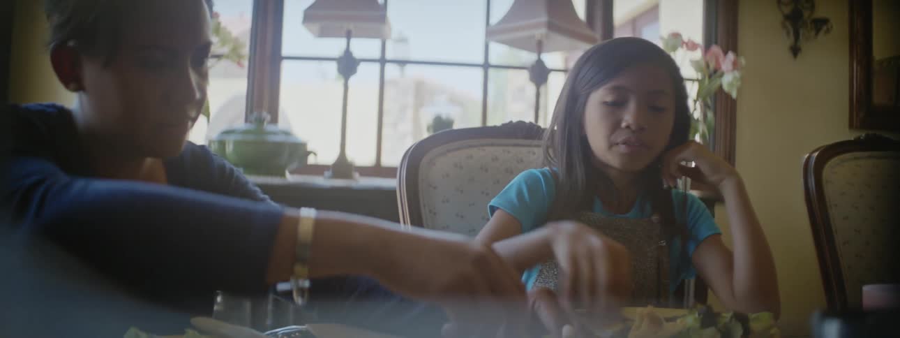 Grandma and granddaughter or momdaughter sitting together at dining table doing crafts and eating lunch