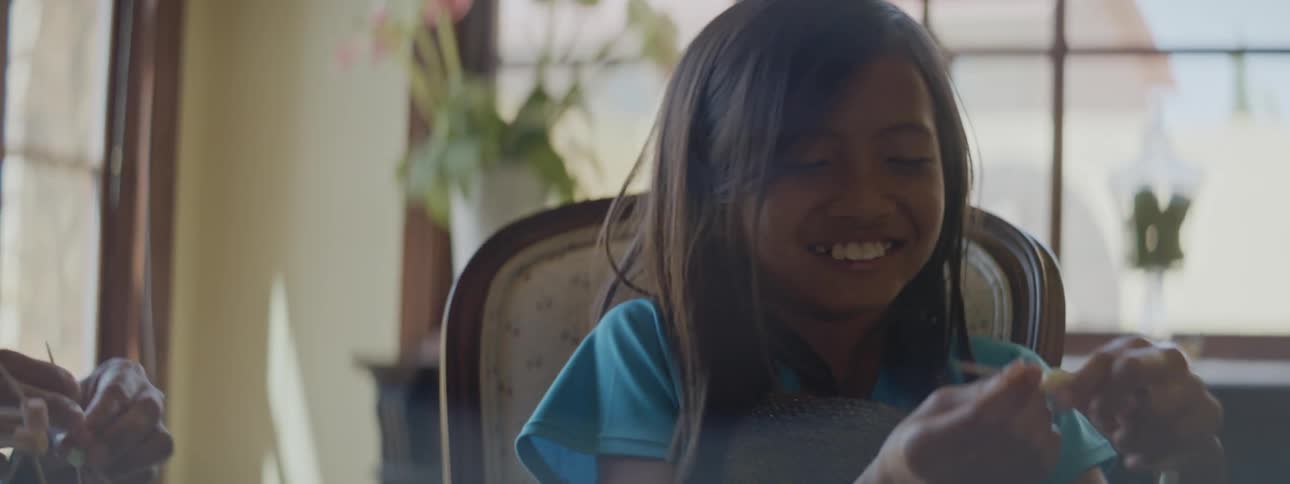 A mother and daughter laugh while building a science project atomic structure out of toothpicks and mini marshmallows in their home dining room