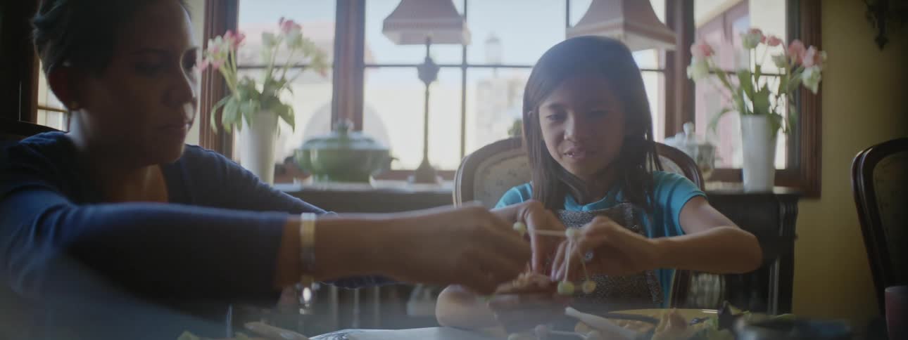 A mother and daughter having a meal at their dining room table build a science project from toothpicks and cotton balls