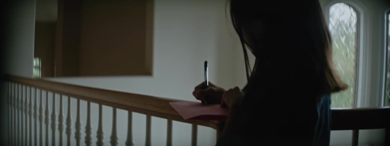 A girl is writing on a piece of paper on the bannister