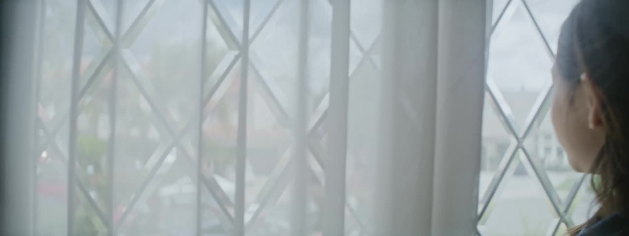 A young girl standing in front of a window tracing the shapes with her fingers