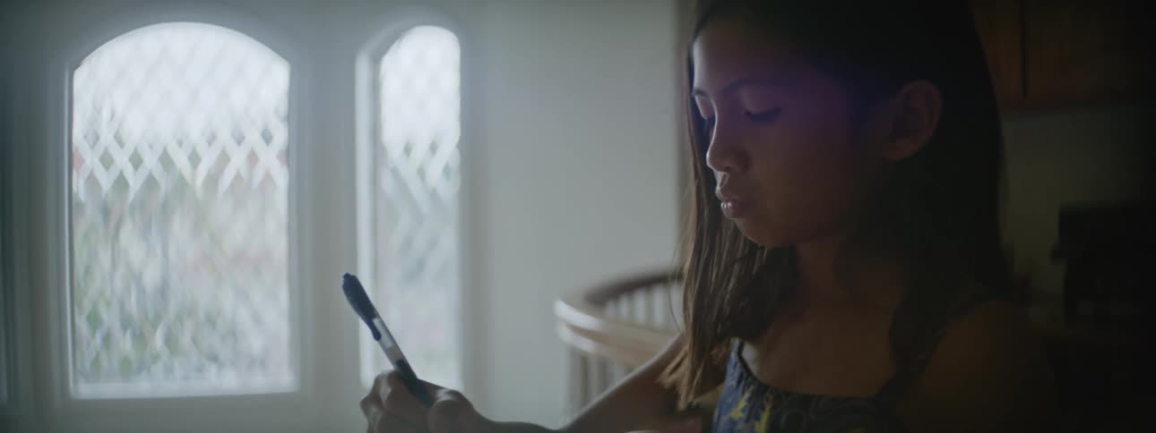 A young girl standing indoors writing with a pen
