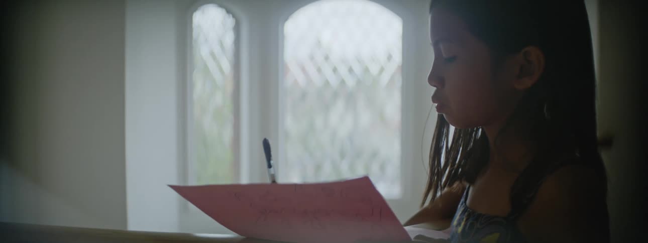 Young girl standing at the top of the stairs at home writing on paper doing homework