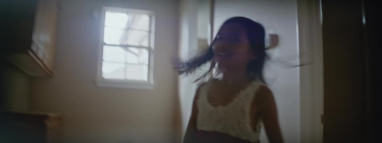 Young girl running through house during the day with a pinwheel that she made
