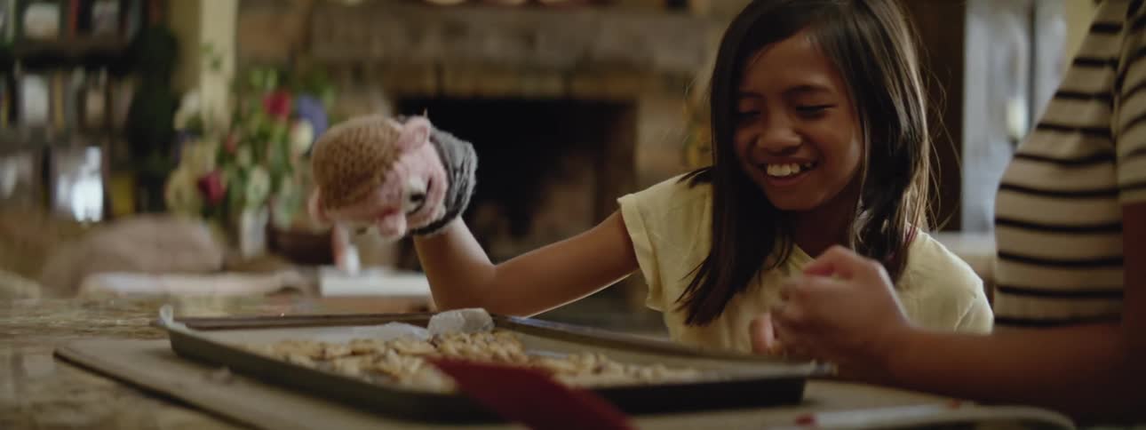 A child plays with a hand puppet while they cook