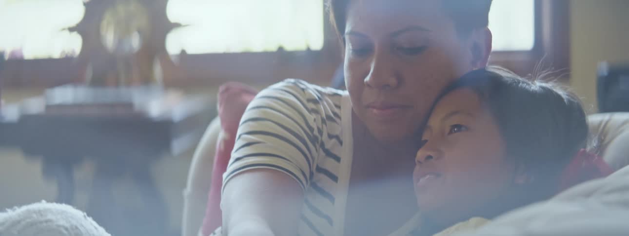 A mother and daughter are hugging and relaxing on the sofa