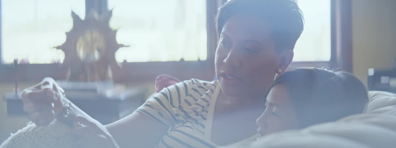 Mother cuddles with daughter on the couch as they talk