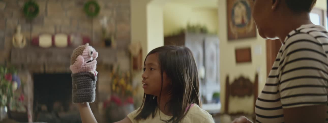 Mother and daughter have fun playing with a puppet in the kitchen at home