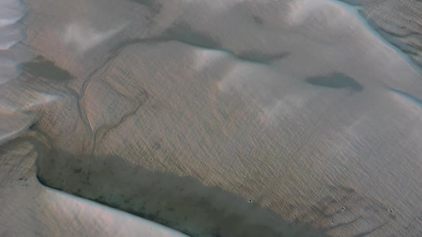 An aerial of a large rock formation with shadows and canyons