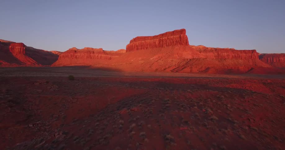 Aerial view of a mesa in the badlands painted red with the sun light at evening