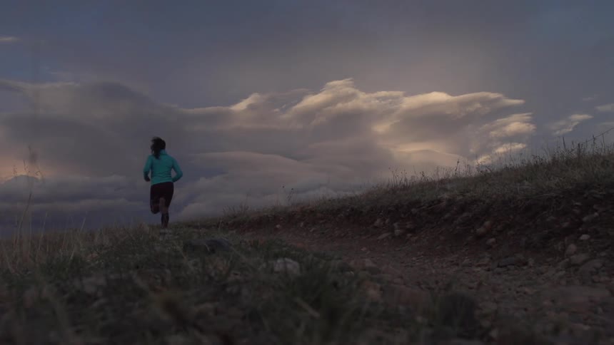 A young woman is jogging outdoors around the forest area
