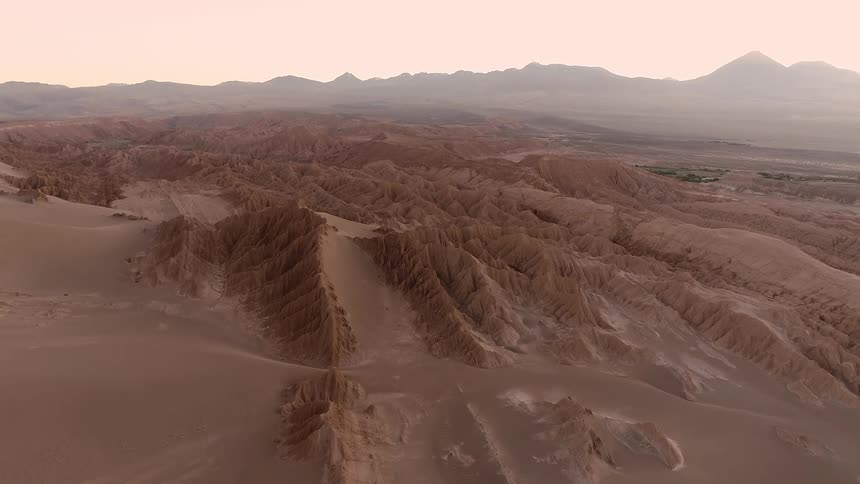 An aerial of desert mountain ranges covered in sand