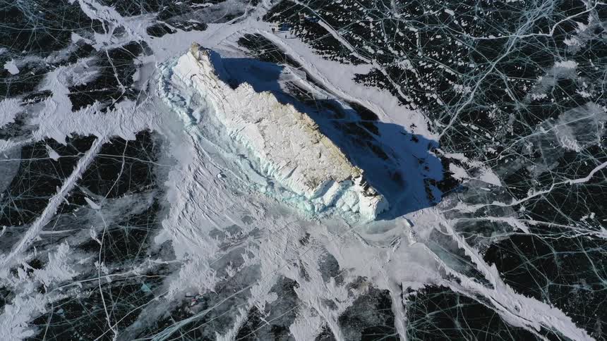 Top down aerial view of an island in the middle of a frozen lake at daytime