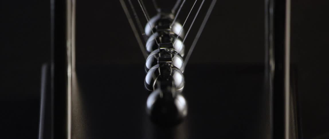 The metal balls on a newtons cradle executive toy swing and collide with one another in slow motion