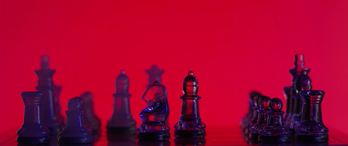 A hand removes a bishop and moves a knight and pawn chess piece across the board against a bright red background