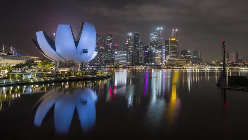 A time lapse of a lake with the cities reflection on it and the buildings lit up at night