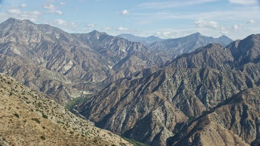 Aerial footage showcasing the stunning mountain ridges and canyon of Sunland-Tujunga California on a partly cloudy day
