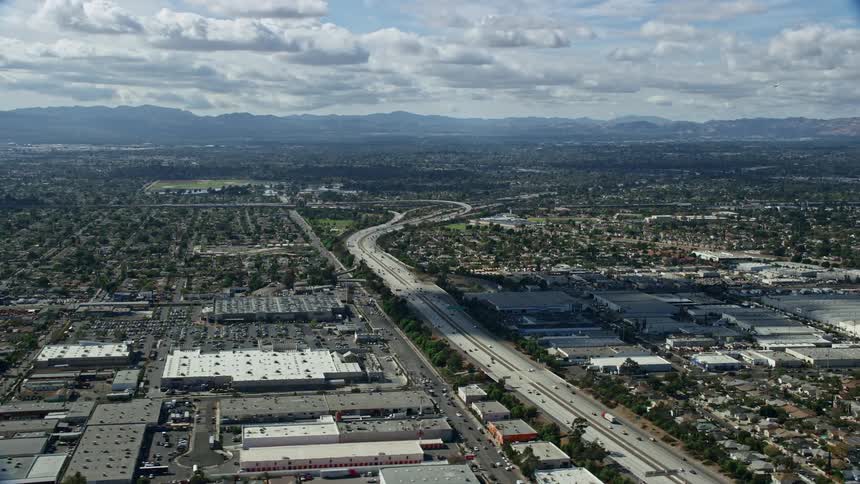 An epic aerial flyover of the 118 freeway and warehouses in Pacoima San Fernando Valley California during partly cloudy skies