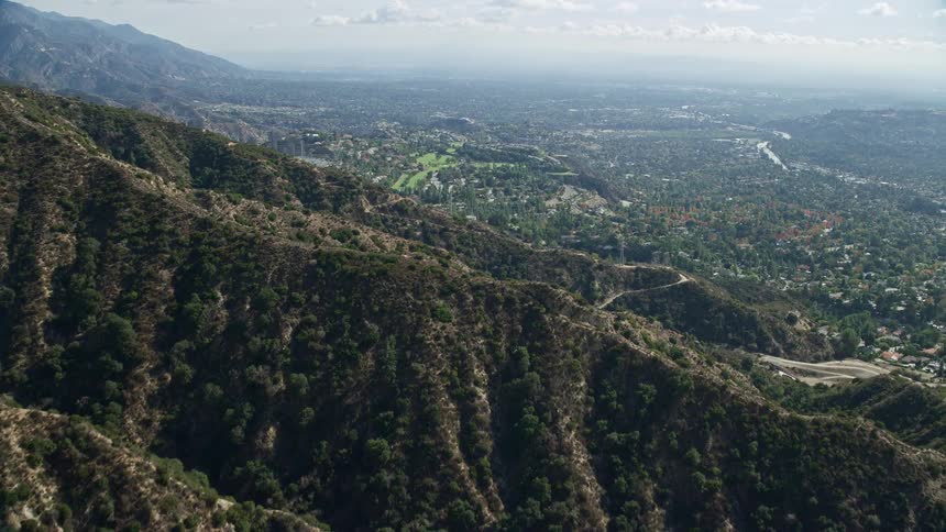 Aerial footage of a Southern California residential community and country club in La Cañada Flintridge shot during the spring or summer with partly cloudy skies