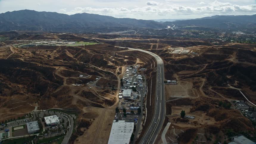 Aerial footage of warehouses and a road in Santa Clarita CA shot during a partly cloudy day