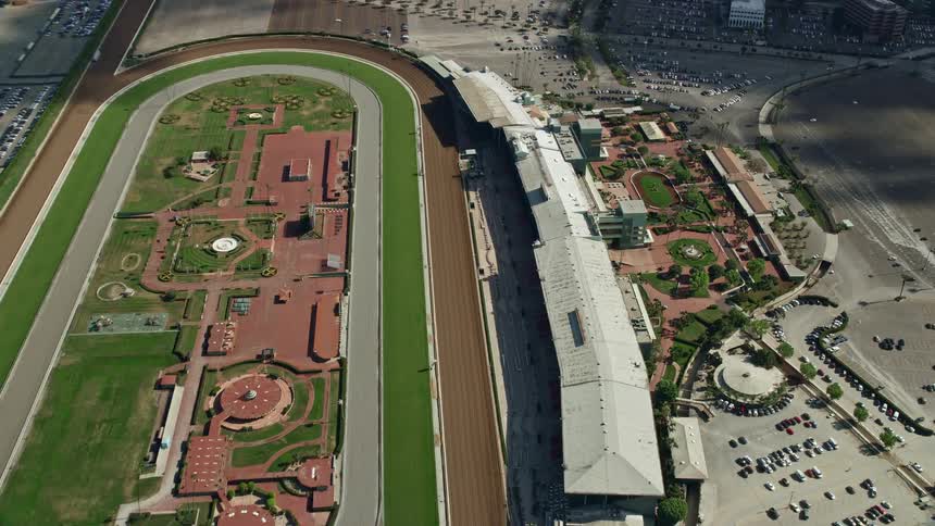 A birds eye and reverse view of the Santa Anita Park horse race track in Arcadia California during a partly cloudy day captured in aerial stock footage