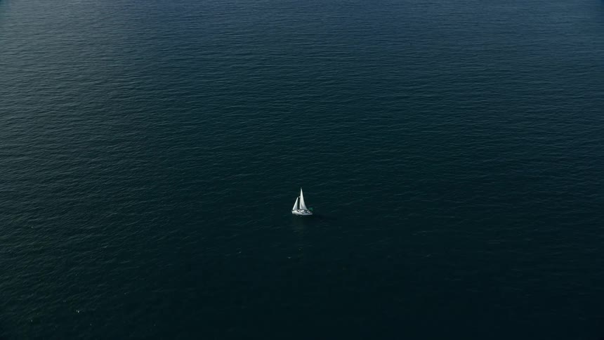 Approaching a sailboat sailing alone in the open waters of Southern California during a partly cloudy day
