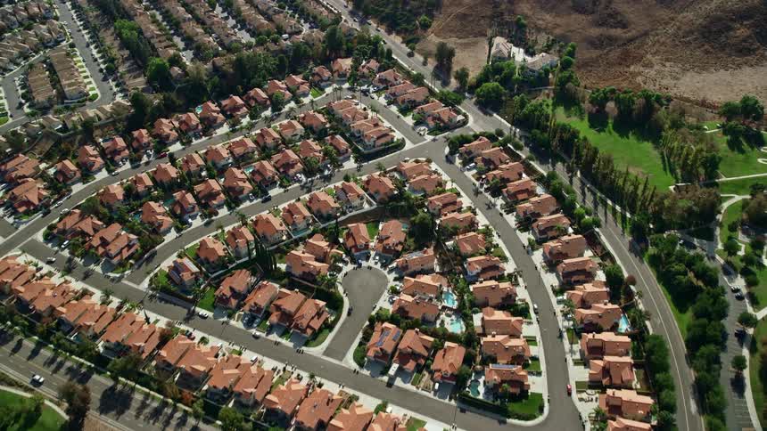 Approaching and tilting down to sunny tract homes in the suburbs of Corona CA during a beautiful summer day