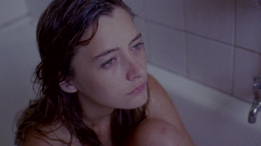 A woman sits in the tub with her knees pulled to her chest