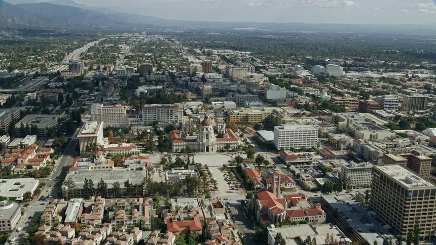 Aerial view flying over an office building and approaching Pasadena City Hall in Southern California with partly cloudy skies