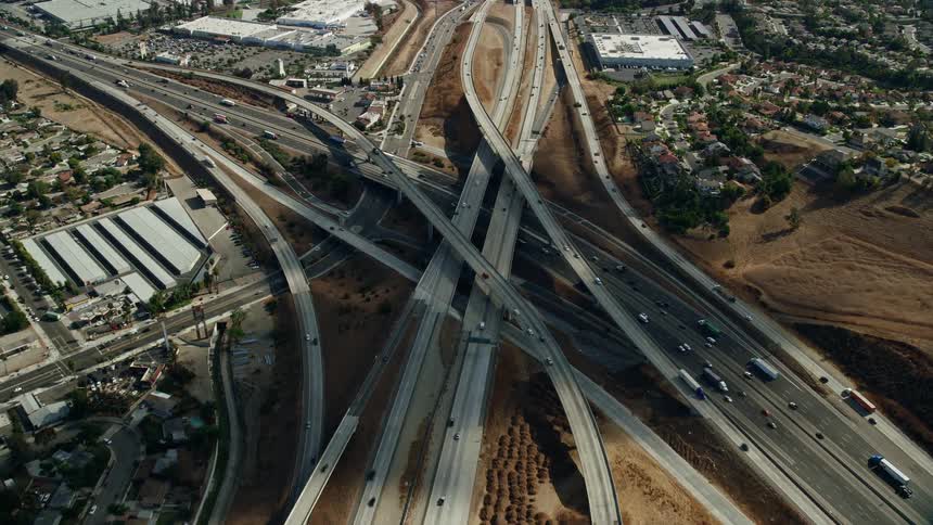 Aerial footage of traffic passing through the Hwy 60 & Hwy 71 Interchange in Pomona California on a partly cloudy day