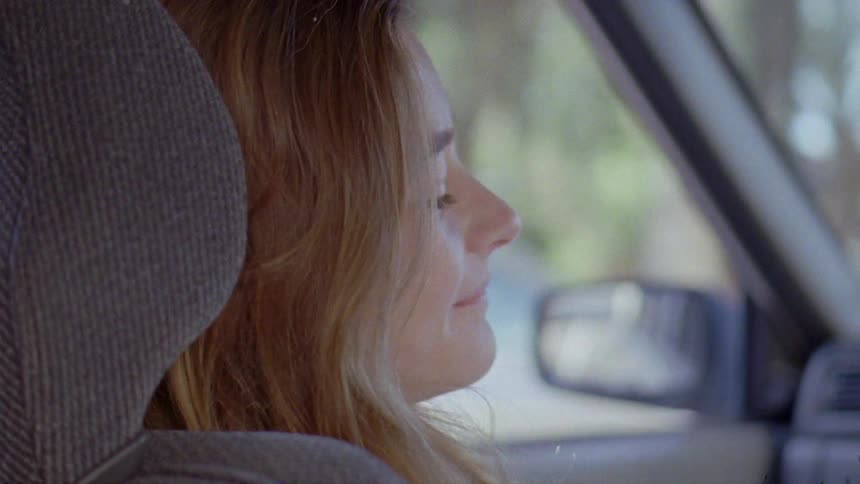A woman drives through a neighborhood