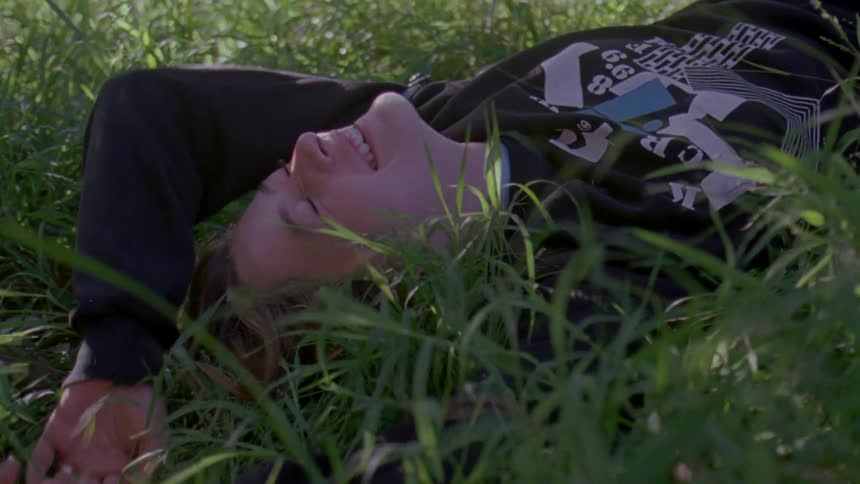 A woman laying on the grass face up laughing and smiling