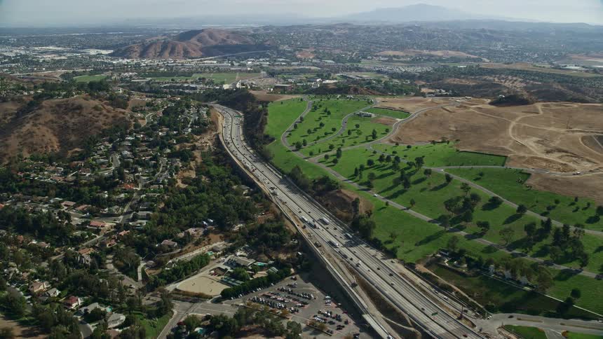 Aerial view of traffic passing through homes and Forest Lawn Covina Hills Cemetery on I-10 freeway in Covina California during daytime