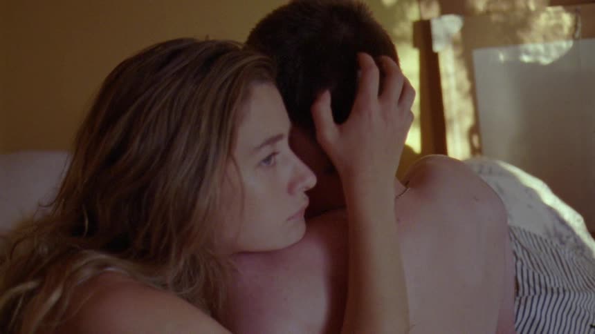 A woman hugs a boy in bed