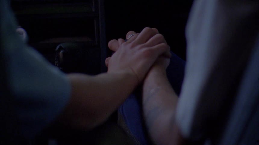 A close up of a man and woman holding hands while in a car driving
