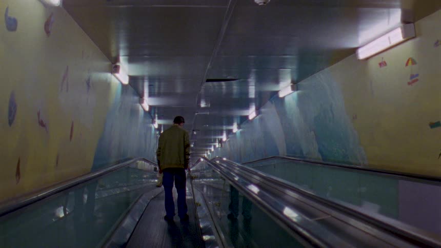 A man rides a horizontal escalator down a corridor
