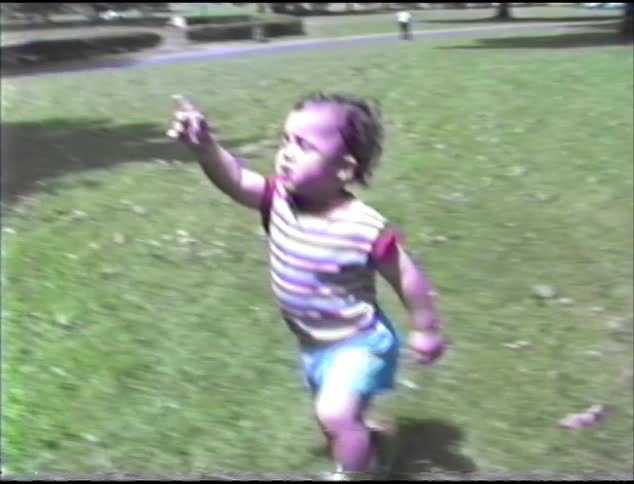 Baby running in grass at the park and talking