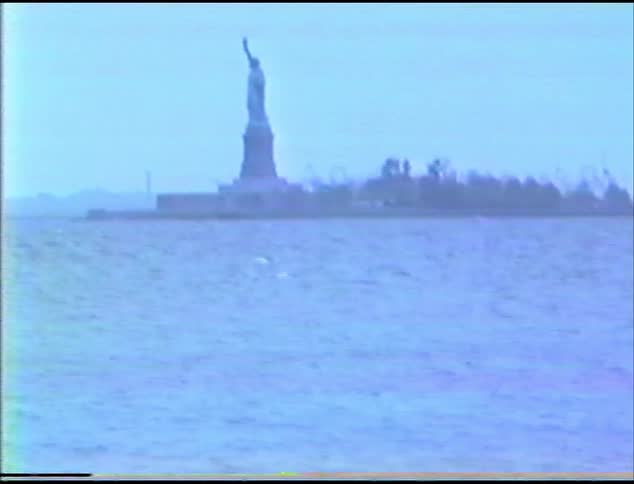 The statue of liberty looms over the ocean on a sunny day