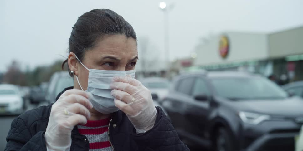 A woman putting on and adjusting a face mask