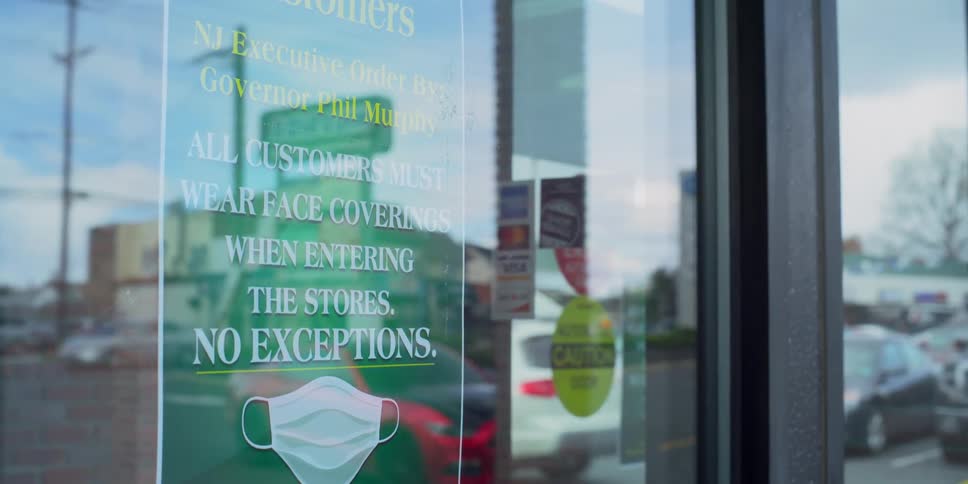 A man walks out of a store with a sign hanging on it as cars drive past