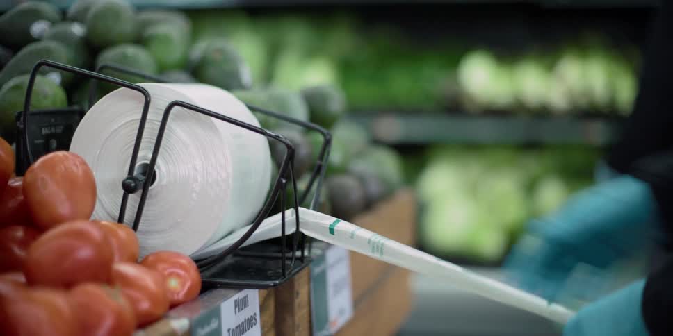 A woman rips a bag off at the grocery store