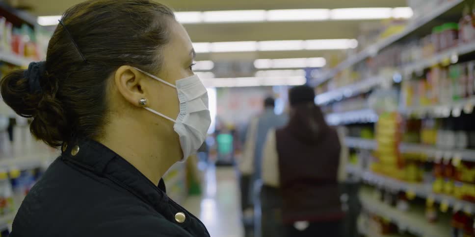 A woman wears a medical face mask while looking at the shelf in a grocery store