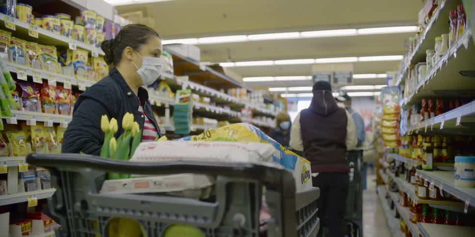 Woman wearing a white face mask buys groceries in the supermarket