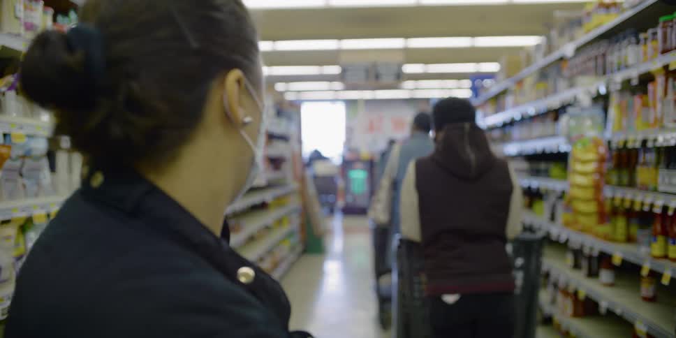 A woman with a mask standing in a line in the supermarket