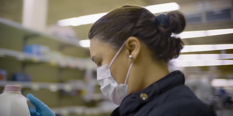 A woman wearing a facemask is grocery shopping