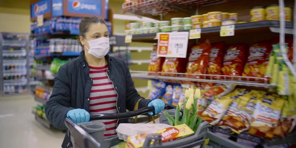 Woman wearing face mask passing aisles while shopping at grocery store