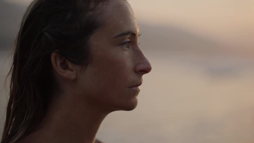 Side profile of woman with brown hair on the coast at sunset